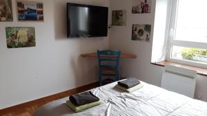 een slaapkamer met een bed en een tv aan de muur bij Chez Cathy in Loscouët-sur-Meu