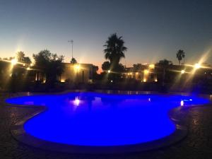 a blue swimming pool at night with lights at Masseria Giamarra in Carpignano Salentino