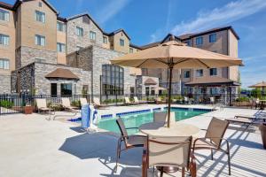 a patio with a table with an umbrella next to a pool at Staybridge Suites Mt Juliet - Nashville Area in Mount Juliet