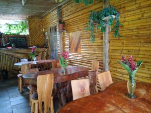 a restaurant with wooden tables and chairs with flowers on them at Hostal El Eden de Mindo in Mindo