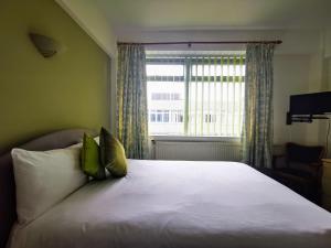 a bedroom with a white bed with a window at Castle Hotel in Merthyr Tydfil