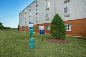 a building with a tree and signs in front of it at Candlewood Suites Bowling Green by IHG in Bowling Green