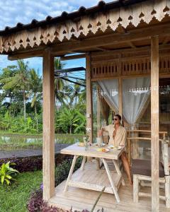 Kidem Ubud Villas في أوبود: رجل يجلس على طاولة في شرفة