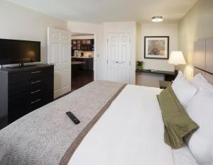 um quarto com uma grande cama branca e uma televisão em Candlewood Suites Dallas NW - Farmers Branch, an IHG Hotel em Farmers Branch