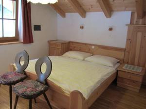 a bedroom with a large bed and two chairs at Appartements Lindenhof in Vandoies