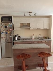 La cuisine est équipée d'un réfrigérateur en acier inoxydable et de tabourets en bois. dans l'établissement Condominio don Alfonso, à Talca