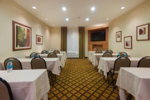 une salle de conférence avec des tables et des chaises blanches et une télévision dans l'établissement Candlewood Suites Fort Worth West, an IHG Hotel, à Fort Worth