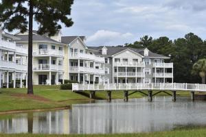 a row of apartment buildings with a bridge over a body of water at Brunswick Plantation Resort and Golf Condo 805M with Full Kitchen in Calabash