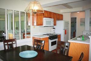 uma cozinha com mesa e cadeiras e uma cozinha com electrodomésticos brancos em 104 villa em Calabash