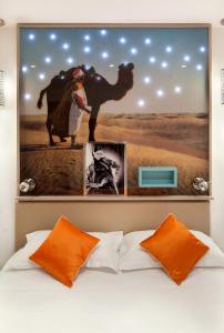 a large painting above a bed with orange pillows at H&ocirc;tel Mayet in Paris