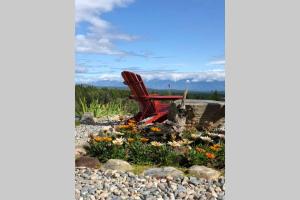 a red chair sitting in a garden with flowers at Mountain Edge Ski-in Ski-out Condo in Kimberley