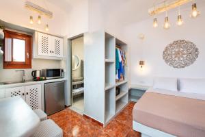 a small bedroom with a bed and a kitchen at Nectarios Villa - Studios & Suites Adults Only in Fira