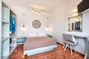 a bedroom with a bed and a chair and a mirror at Nectarios Villa - Studios & Suites Adults Only in Fira