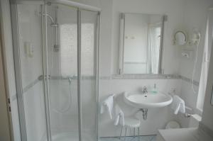 a white bathroom with a sink and a shower at Parkhotel Goldlinde in Bodenwerder +72 photos