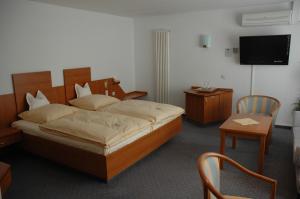 a bedroom with a bed and a tv and a chair at Parkhotel Goldlinde in Bodenwerder
