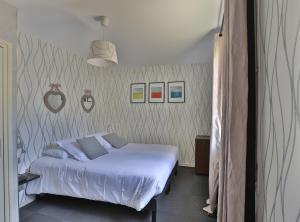Un dormitorio con una cama blanca y algunas fotos en la pared en Logis Hotel Des Grands Vins, en Fleurie