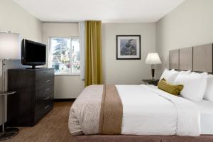 a hotel room with a large bed and a flat screen tv at Candlewood Suites Durham - RTP by IHG in Durham