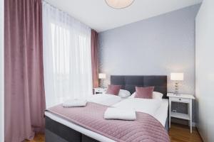 um quarto com uma cama grande com lençóis brancos e almofadas cor-de-rosa em NY Residence Apartments Wrocławska Cracow by Renters Prestige em Cracóvia