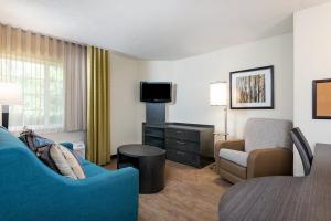 a hotel room with a couch and a chair and a table at Candlewood Suites Durham - RTP by IHG in Durham