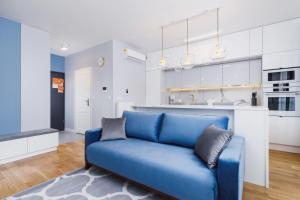 um sofá azul numa sala de estar com uma cozinha em NY Residence Apartments Wrocławska Cracow by Renters Prestige em Cracóvia