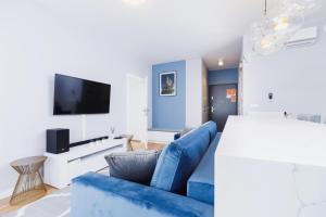 uma sala de estar com um sofá azul e uma televisão de ecrã plano em NY Residence Apartments Wrocławska Cracow by Renters Prestige em Cracóvia