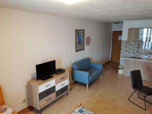a living room with a blue chair and a television at Apartmani Prova 4 in Tisno