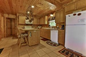 a kitchen with wooden cabinets and a white refrigerator at CABIN TIME - When you need to relax and unwind a visit to Cabin Time is what you need! in Mineral Bluff