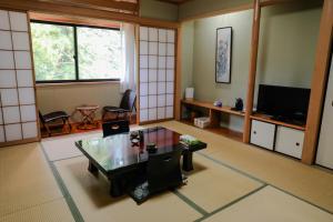 sala de estar con mesa y TV en Ajisai Onsen Ryokan, en Hakone