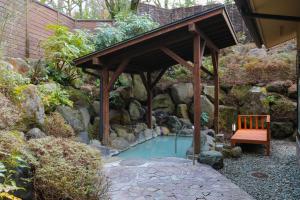 une petite piscine dans un jardin avec un banc en bois dans l'établissement Ajisai Onsen Ryokan, à Hakone