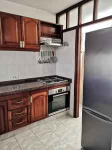 una cucina con armadi in legno e frigorifero in acciaio inossidabile di Fantastic Bungalow Playa de Las Américas ad Arona