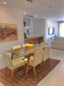 une salle à manger avec une table en verre et des chaises blanches dans l'établissement Flat 3 suites frente mar, à Florianópolis