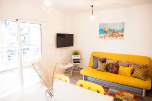 uma sala de estar com um sofá amarelo e uma televisão em Apartment near the beach em Alicante