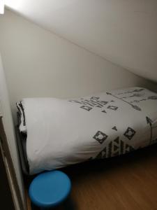 uma pequena cama num quarto com um banco azul em Chez Pat & Mat em La Canourgue