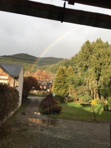 un arco iris sobre un patio con una casa en Bungalows Luz del sur en San Carlos de Bariloche