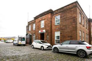 two cars parked in front of a brick building at OYO Gin House Hotel in Greenock