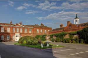 un grand bâtiment en briques avec une fontaine devant lui dans l'établissement SK Baylis House Hotel, à Slough