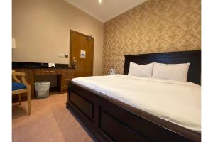 a bedroom with a large bed with a desk and a bed sidx sidx at SK Baylis House Hotel in Slough
