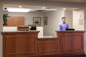 a man standing behind a counter in a waiting room at Candlewood Suites La Crosse, an IHG Hotel in La Crosse