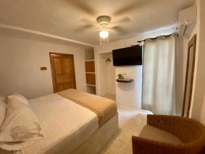a bedroom with a bed and a television and a chair at MIO Cancún Hotel Boutique in Cancún
