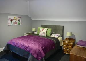 a bedroom with a purple bed and a wooden dresser at Cottage 33 Old Killarney Village Killarney in Killarney
