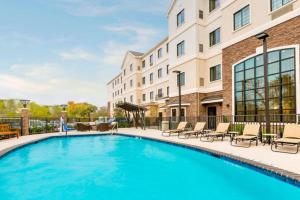 a swimming pool with chairs and a building at Staybridge Suites College Station, an IHG Hotel in College Station