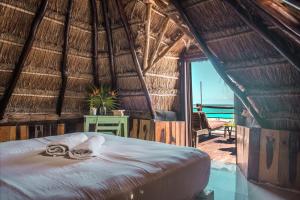 1 dormitorio con 1 cama en una habitación con techo de paja en Playa Esperanza Tulum en Tulum