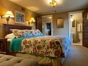 a bedroom with a bed with a flowered blanket and a bathroom at Kangaroo House Bed & Breakfast in Eastsound