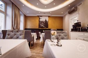 um restaurante com mesas e cadeiras brancas e um copo de vinho em Golden Key Boutique Hotel em Karlovy Vary