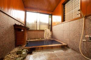 a bath tub in a room with a window at Kappo Ryokan Kannawa Bettei in Beppu