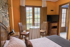 1 dormitorio con 1 cama y 1 mesa con sillas en Hotel Rural Casa Paulino, en Taramundi