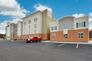 um carro vermelho estacionado em frente a um grande edifício em Candlewood Suites Harrisburg-Hershey, an IHG Hotel em Harrisburg