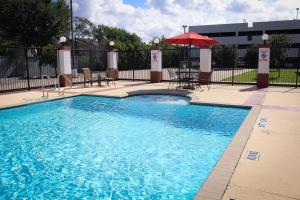 a swimming pool with a table and an umbrella at Candlewood Suites Houston Westchase - Westheimer by IHG in Houston