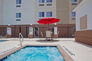 a pool with a red umbrella and a table and chairs at Candlewood Suites Houston Westchase - Westheimer, an IHG Hotel in Houston