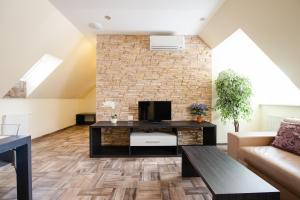 a living room with a tv and a brick wall at Apartments Brigitte in Bratislava